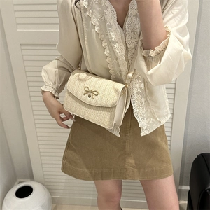 Sac bandoulière tissé avec noeud doré assorti à une chemise blanche et jupe en velours