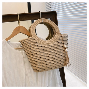Détail du sac à main en paille tissée avec pois noirs et décor de glands en perles de bois