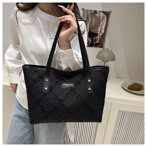 Close-up of black tote bag featuring sparkling fabric texture and metal rivet reinforcement