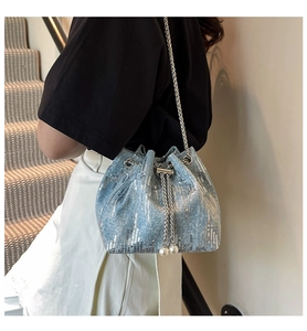 Detail of light blue denim bucket bag featuring silver sequins and elegant pearl charms