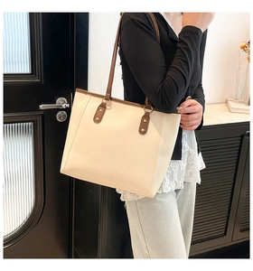 Detail of metal rivet reinforcement and round ring on beige commuter tote bag shoulder strap