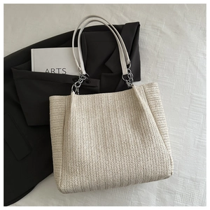 Detail of herringbone woven texture on a cream tote bag with elegant leather handles