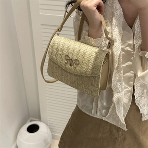 Détail du sac à bandoulière en paille tissée avec fermoir nœud doré et rabat chic