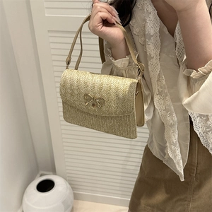 Détail du sac bandoulière en paille tressée avec boucle nœud doré et fine bandoulière