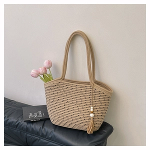 Detail of beige woven tote bag with black polka dots, wooden beads, and pink tulips decoration