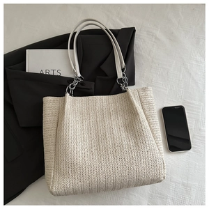 Close-up of large woven tote bag with herringbone texture and chain leather strap