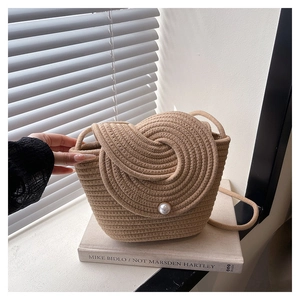 Détail du sac seau tressé avec couvercle en spirale et fermoir en perle élégant