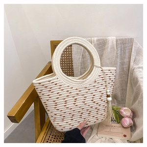 Détail de sac en paille avec pois marrons et pampille de perles en bois avec frange