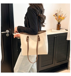 Detail of minimalist cream tote bag with brown contrast trim in a modern home setting