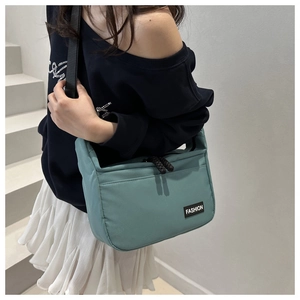 Détail du sac bandoulière en nylon sarcelle avec fermeture éclair et étiquette