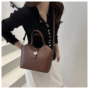 Detail view of a vintage brown leather bucket bag with silver metal buckle on stairs
