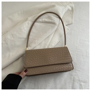 Detailed view of khaki woven baguette bag with intricate cross-weave texture and strap