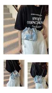Detail of light blue sequined bucket bag featuring silver chain and pearl drawstring charms