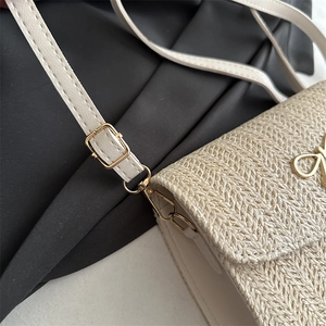 Détail du sac bandoulière blanc tissé avec nœud doré et boucle de sangle ajustable