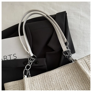 Detail of straw tote bag featuring herringbone weave and silver metal chain strap