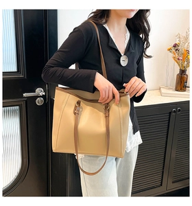 Detail of minimalist cream tote bag with contrast stitching and golden D-ring connectors