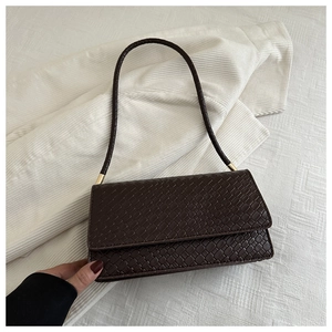 Close-up of brown crocodile texture leather and golden metal hardware on shoulder bag