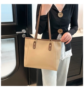 Detail of minimalist tote bag showing golden ring attachment and brown leather shoulder strap