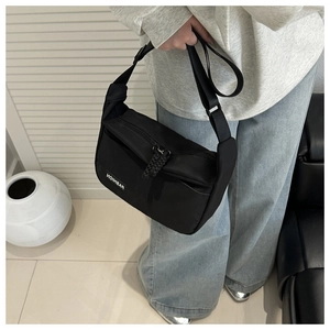 Gros plan sur le sac bandoulière en nylon noir avec sangle réglable et étiquette de mode