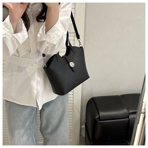 Detail of black leather tote bag featuring a metallic ring buckle and adjustable strap