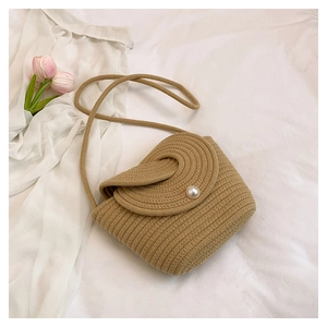 Détail du sac seau en paille tressée avec fermoir perle et bandoulière élégante en corde