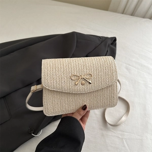 Détail du sac bandoulière tressé crème avec nœud doré et bandoulière en cuir souple