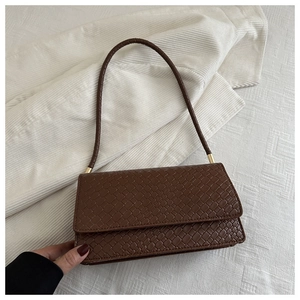 Detail shot of the deep brown woven texture and gold metal hardware on the shoulder bag