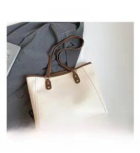 Detail of cream tote bag with contrast brown trim and golden metal studs for office