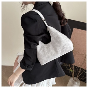 Detail shot of white textured shoulder bag with woven strap detail and crescent moon shape