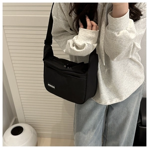 Détail d'un sac bandoulière léger en nylon noir avec sangle réglable pour un usage quotidien
