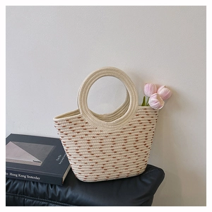 Détail du sac à main en paille tissée avec accents bruns sur un siège en cuir et fleurs