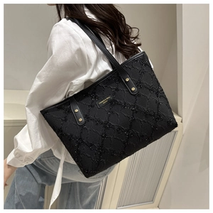 Detailed view of black quilted tote bag featuring shimmering glitter finish and gold hardware