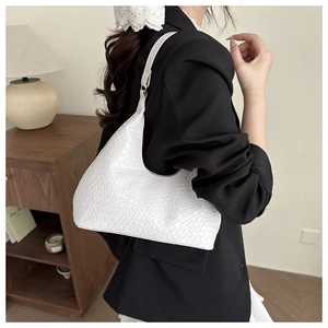 Detail of white woven texture on a minimalist crescent-shaped shoulder bag