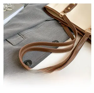 Close-up of contrast tote bag shoulder straps with gold rings and double stitching