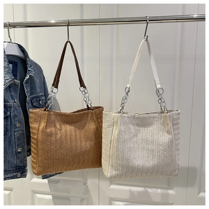 Detail of herringbone weave and metal chain leather straps on straw tote bags
