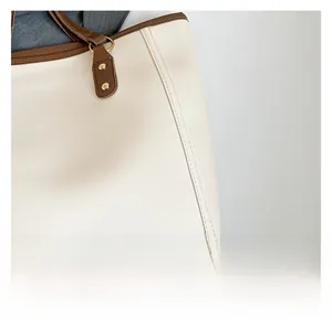Detail of cream tote bag showing premium faux leather texture and gold rivet hardware