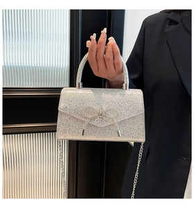 Detailed view of silver sequin evening bag with rhinestone bow and metal handle