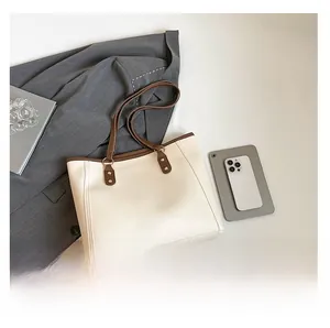 Top-down view of a cream and brown tote bag with metal hardware and office accessories