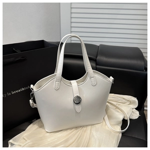 Detailed close-up of white leather handbag with silver round buckle and metallic ring accents