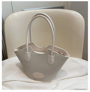 Détail du sac seau tressé crème avec bordure en zigzag et plaque de mode gravée