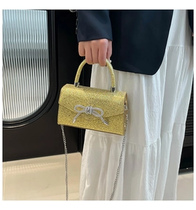 Detail of evening bag with gold sequins, diamond bow, and metal chain strap