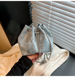 Close-up of blue denim bucket bag featuring silver sequins and pearl drawstring detail