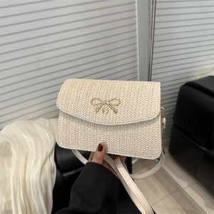 Dettaglio borsa a tracolla in paglia beige con elegante chiusura metallica a fiocco d'oro