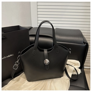Close-up of black matte leather tote bag with silver magnetic buckle and adjustable strap