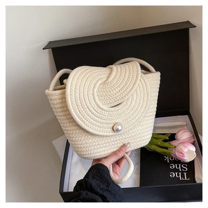 Détail d'un sac seau tressé couleur avoine avec un grand fermoir en perle