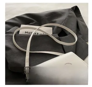 Detail of white square bag with crystal butterfly buckle on a grey suit jacket