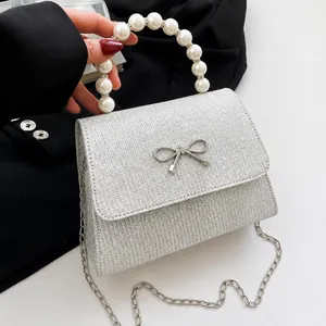 Detailed view of silver sequin bag with pearl handle and metal bow decoration