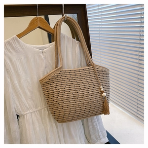 Detail of woven straw tote bag with black polka dots and ethnic tassel charm