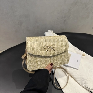 Détail macro du tissage beige et de la boucle dorée en forme de nœud du sac bandoulière