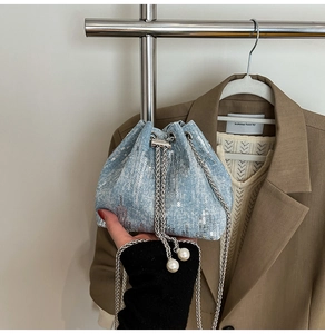 Detail of light blue denim bucket bag with silver sequins and pearl drawstring
